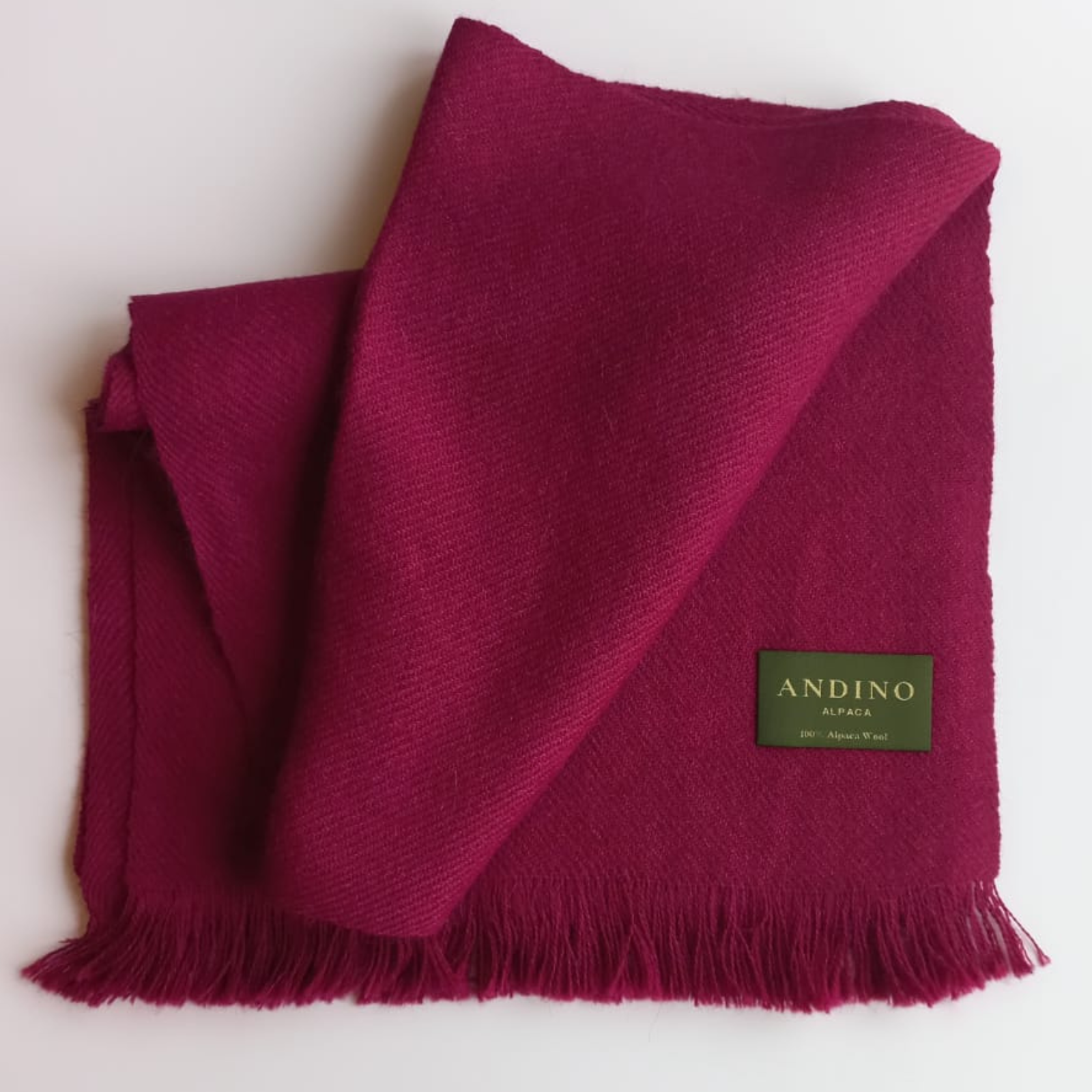 Dark grey large alpaca wool scarf shawl folded and slightly opened on white background with Andino Alpaca logo print.