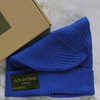 Royal blue alpaca wool beanie hat next to its box on a marble table.