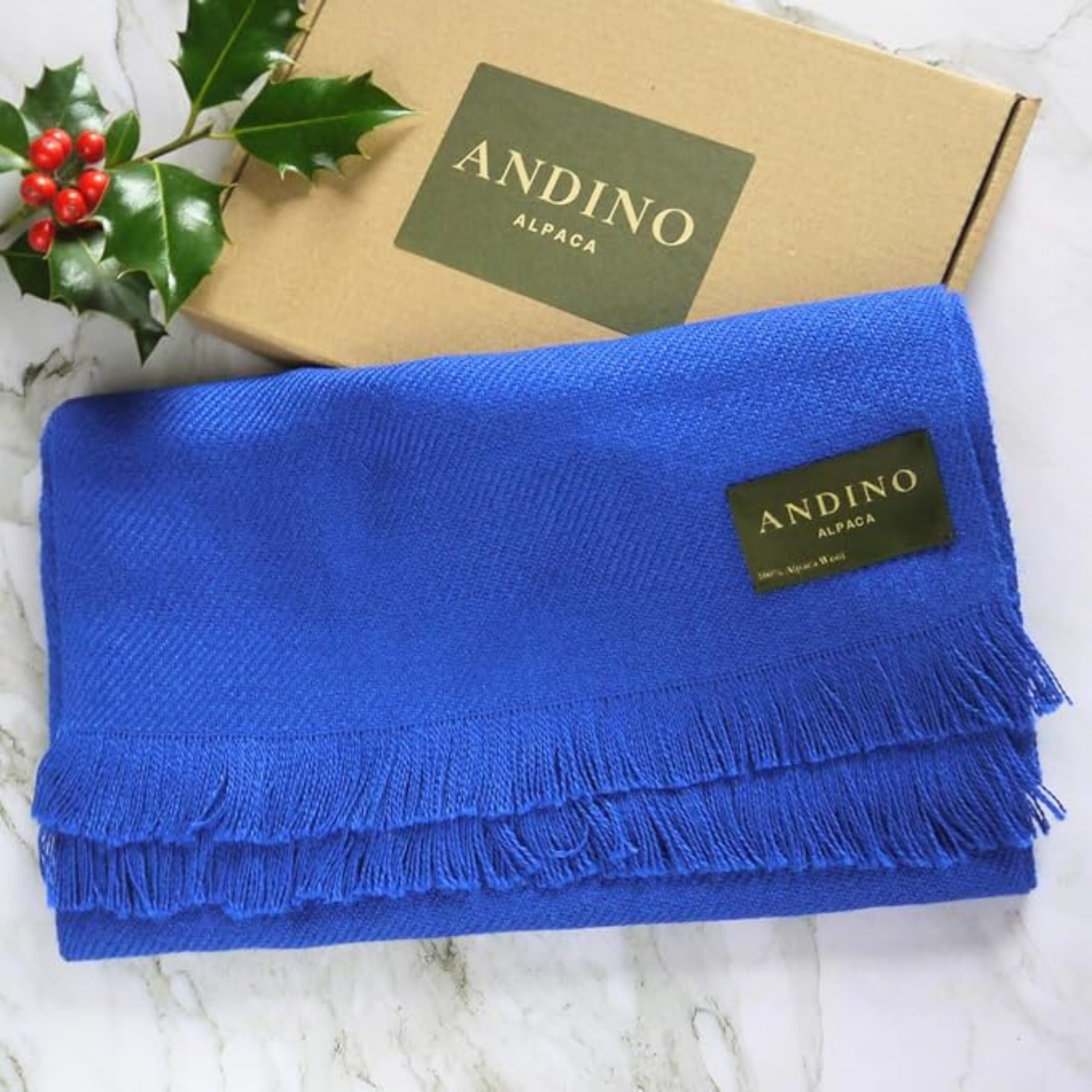 Royal blue alpaca wool scarf on top of its Andino alpaca box on a white marble table