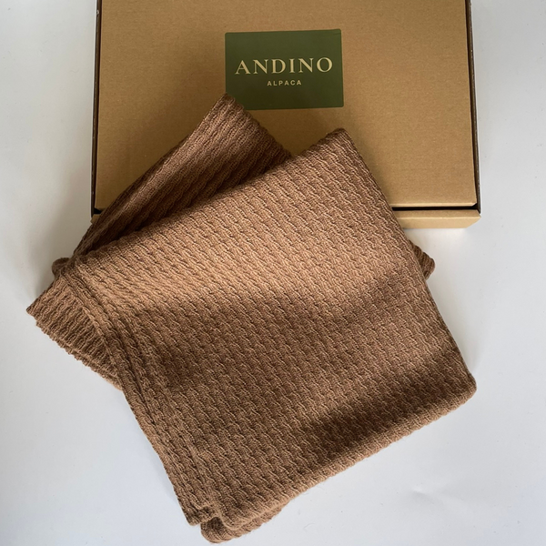 Two brown alpaca cushion covers folded sitting over a box.