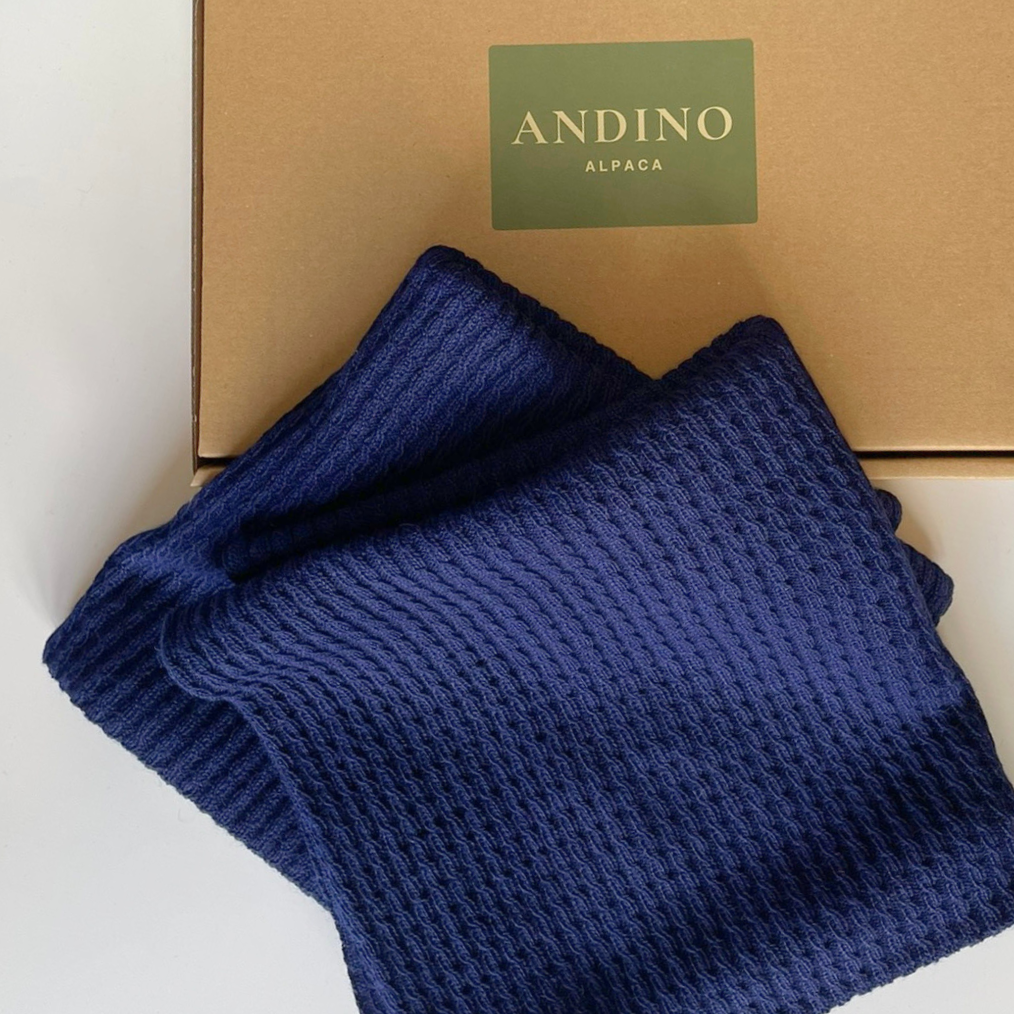 Two navy blue alpaca cushion covers folded sitting over a box.
