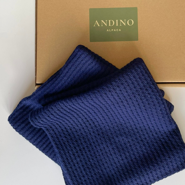 Two navy blue alpaca cushion covers folded sitting over a box.