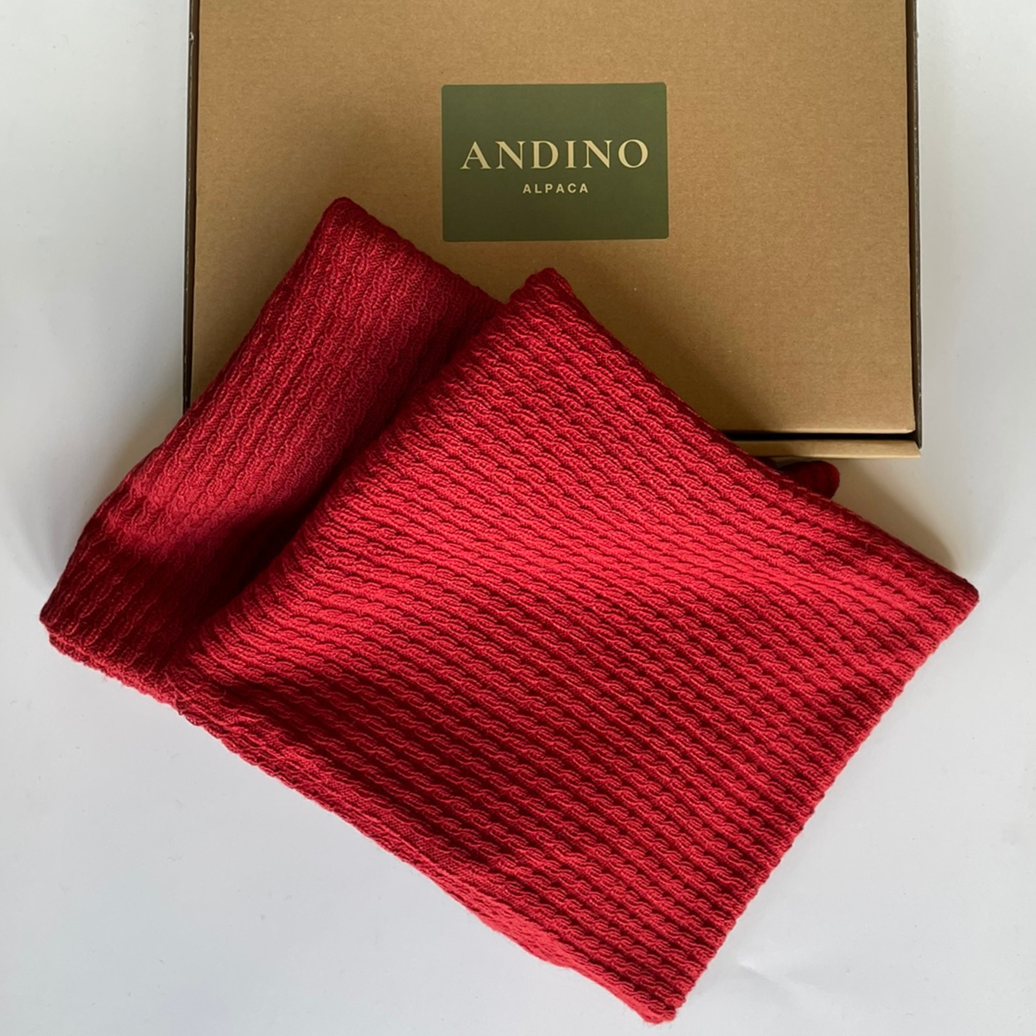 Two red alpaca cushion covers folded sitting over a box