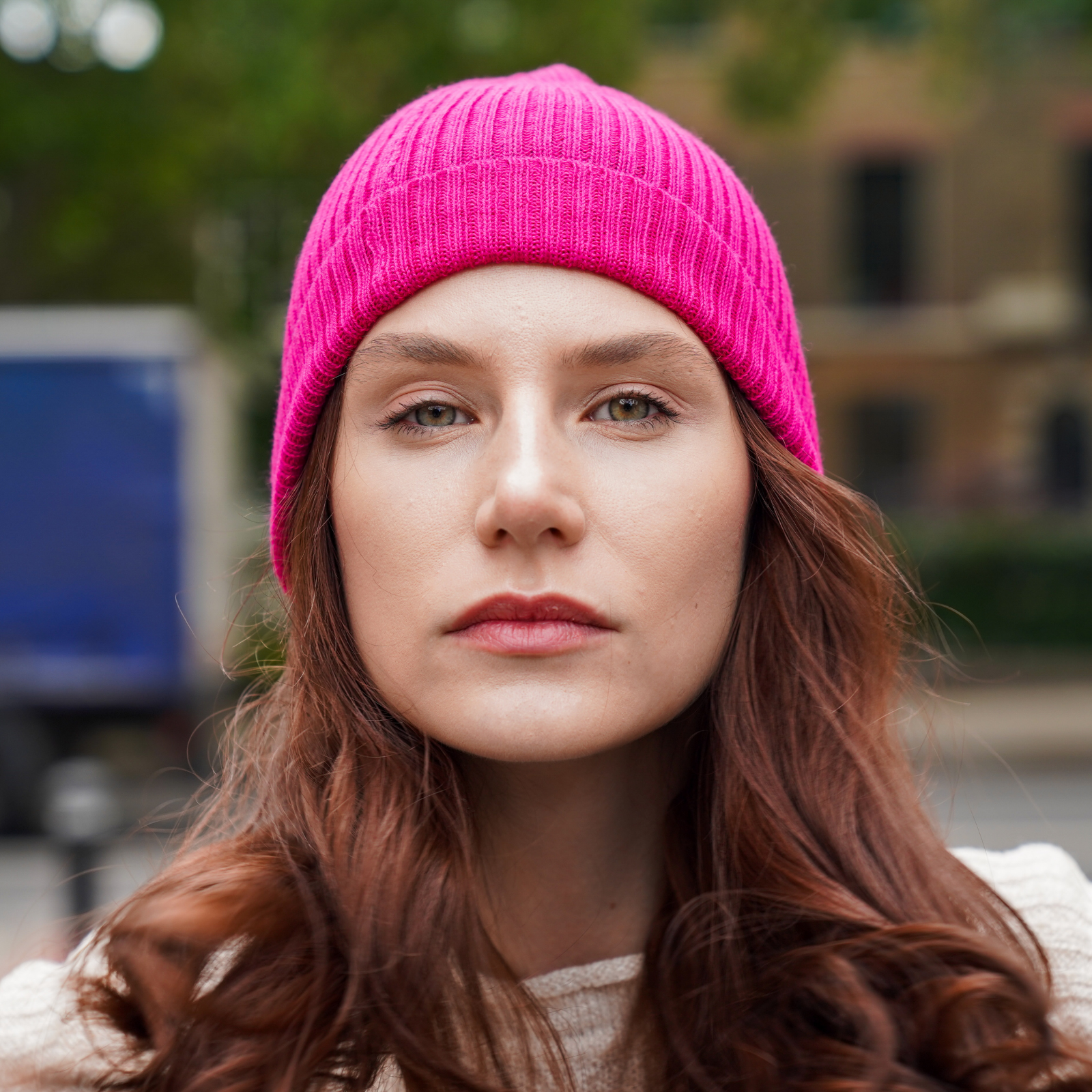 Young man wearing Dark grey alpaca beanie hat outdoors in front of a brick wall.