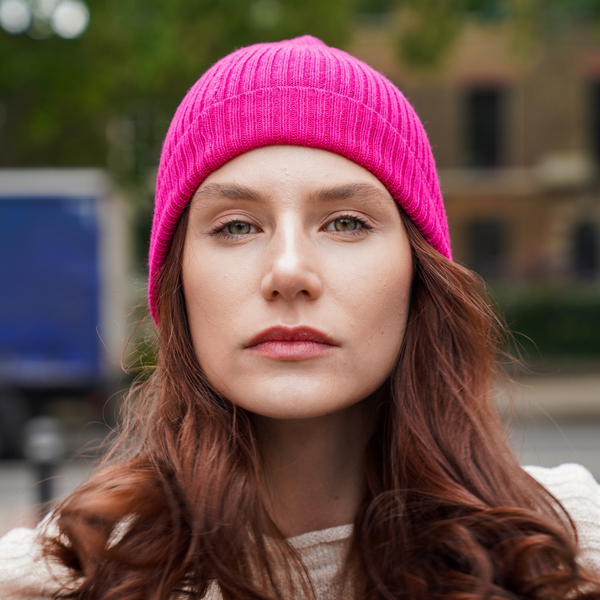 Young man wearing Dark grey alpaca beanie hat outdoors in front of a brick wall.