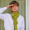 Young man wearing olive green large alpaca wool scarf shawl with a white shirt.