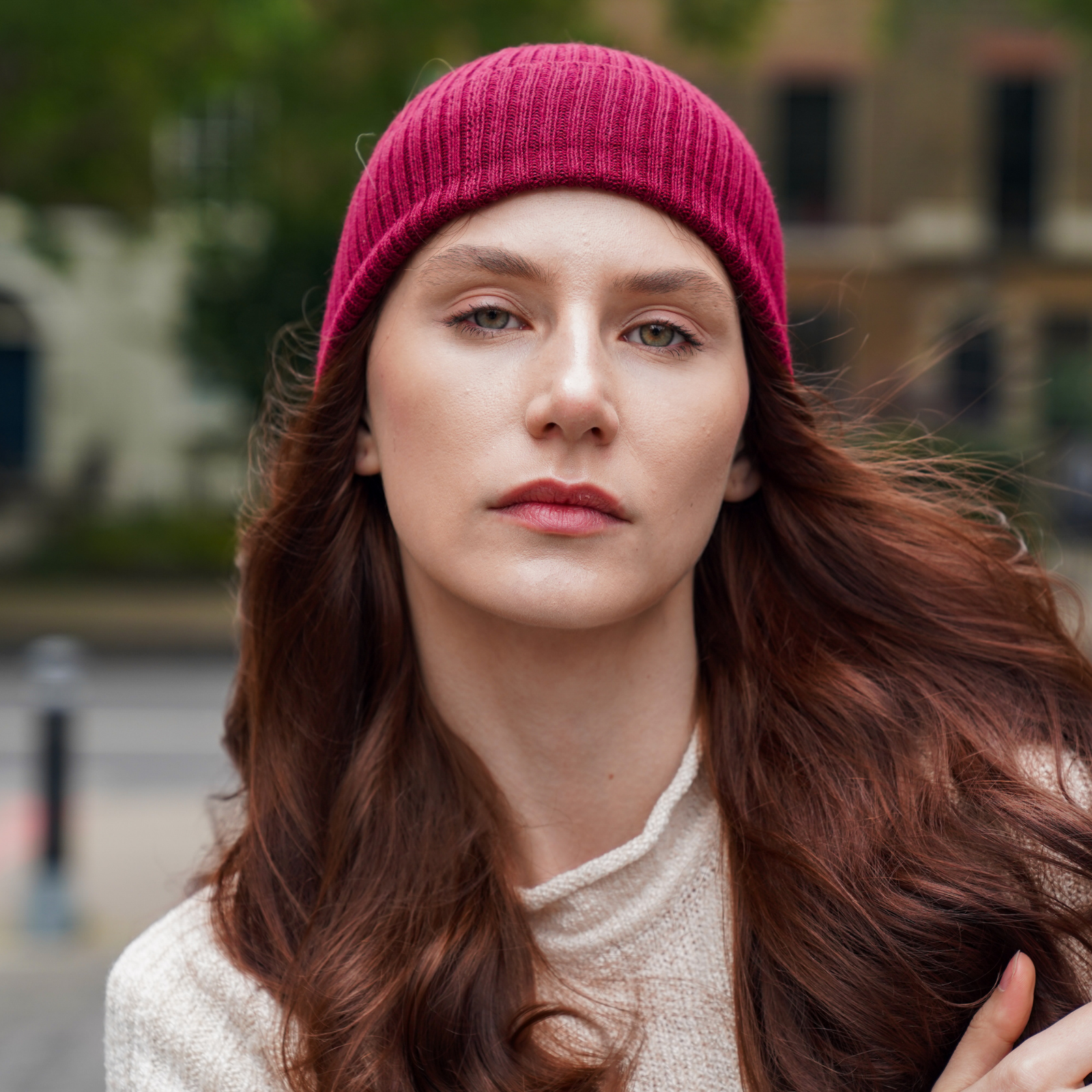 Young woman wearing Burgundy alpaca beanie hat in an outdoor setting in a city.