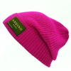 Young woman wearing pink alpaca beanie hat in an outdoor setting in a city.
